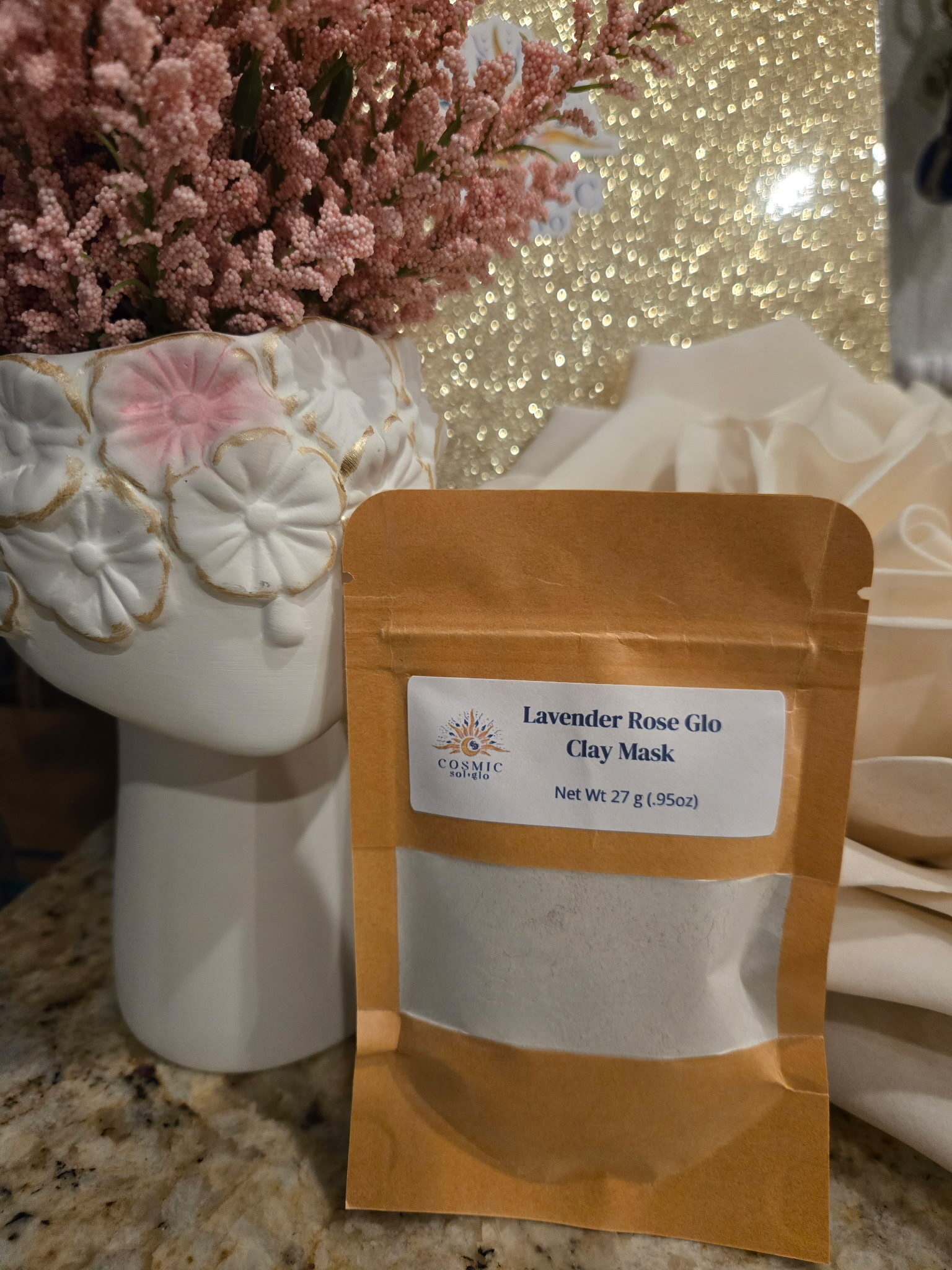 Lavender Rose Glo clay mask pouch styled with pink flowers and gold glitter
