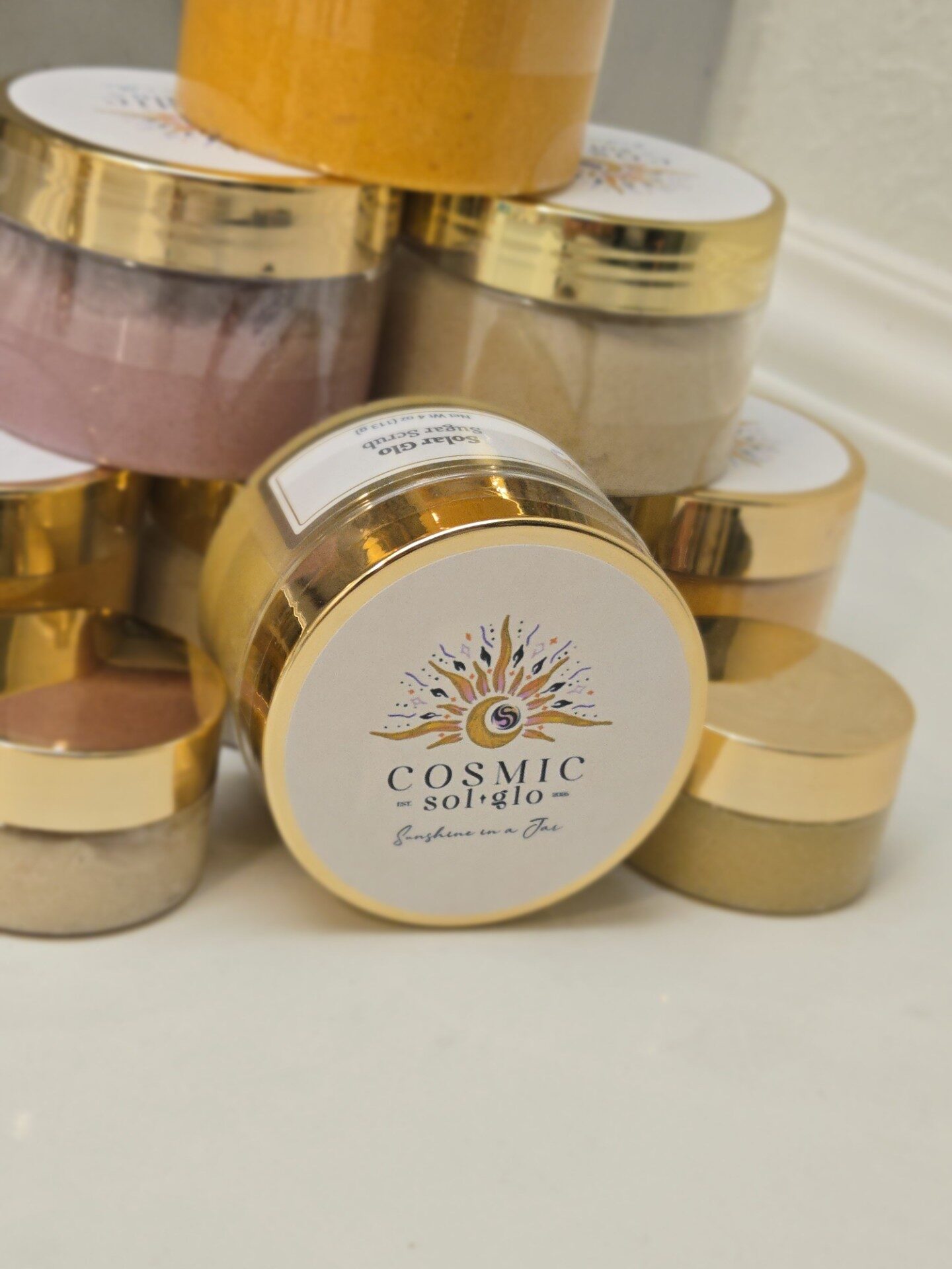 Solar Glo sugar scrub jar, gold lid, front label visible among the collection