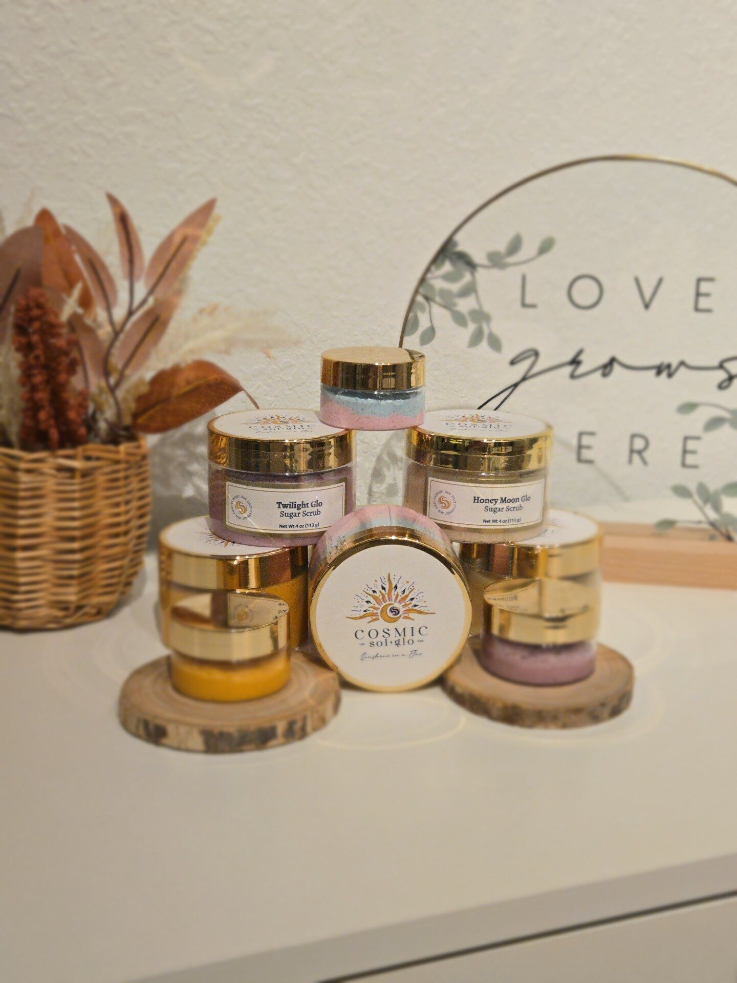 A colorful collection of Cosmic Sol Glo jars beside a 'Love grows here' sign