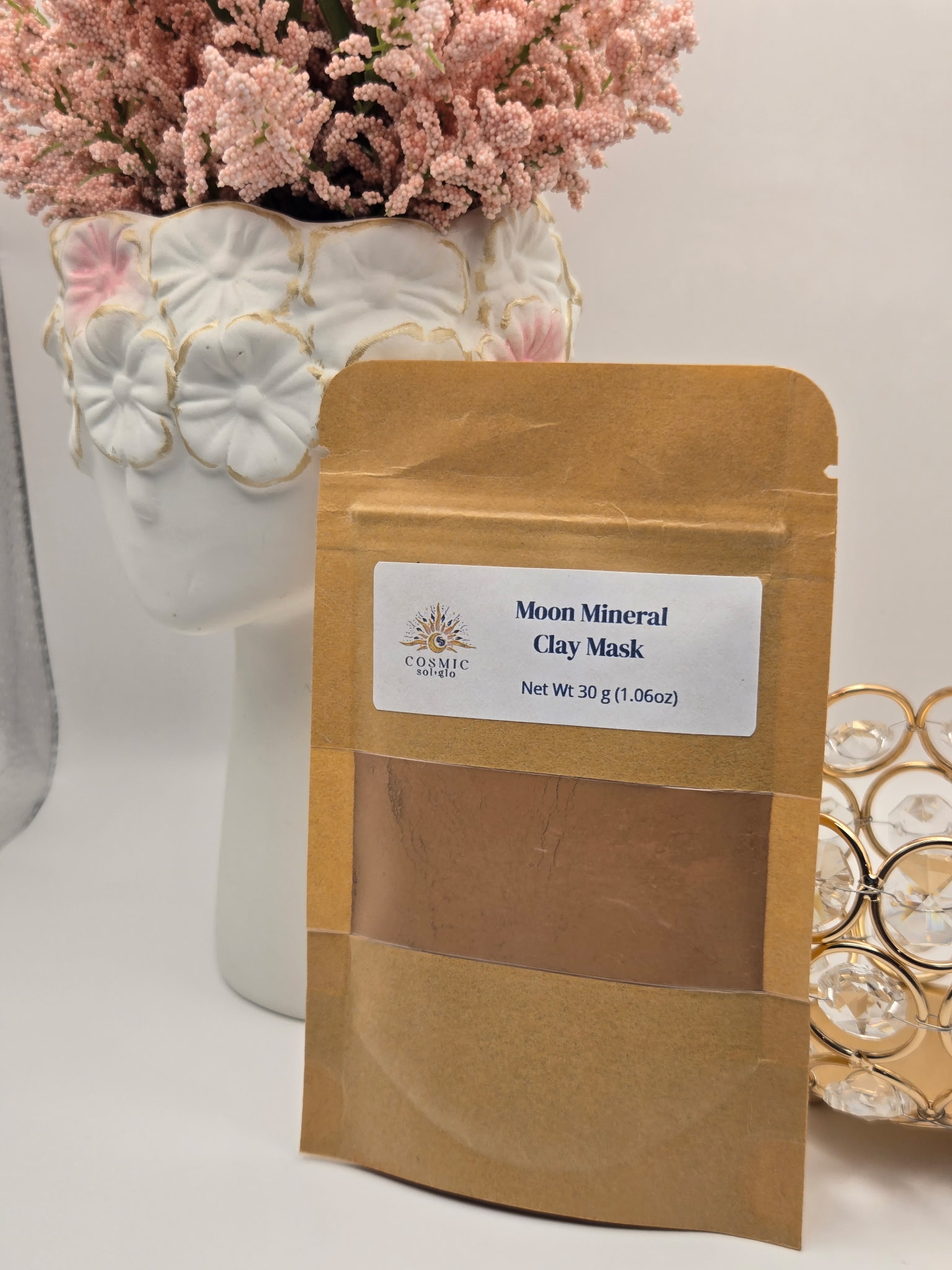Moon Mineral Clay Mask pouch styled with dried pink flowers in a white vase